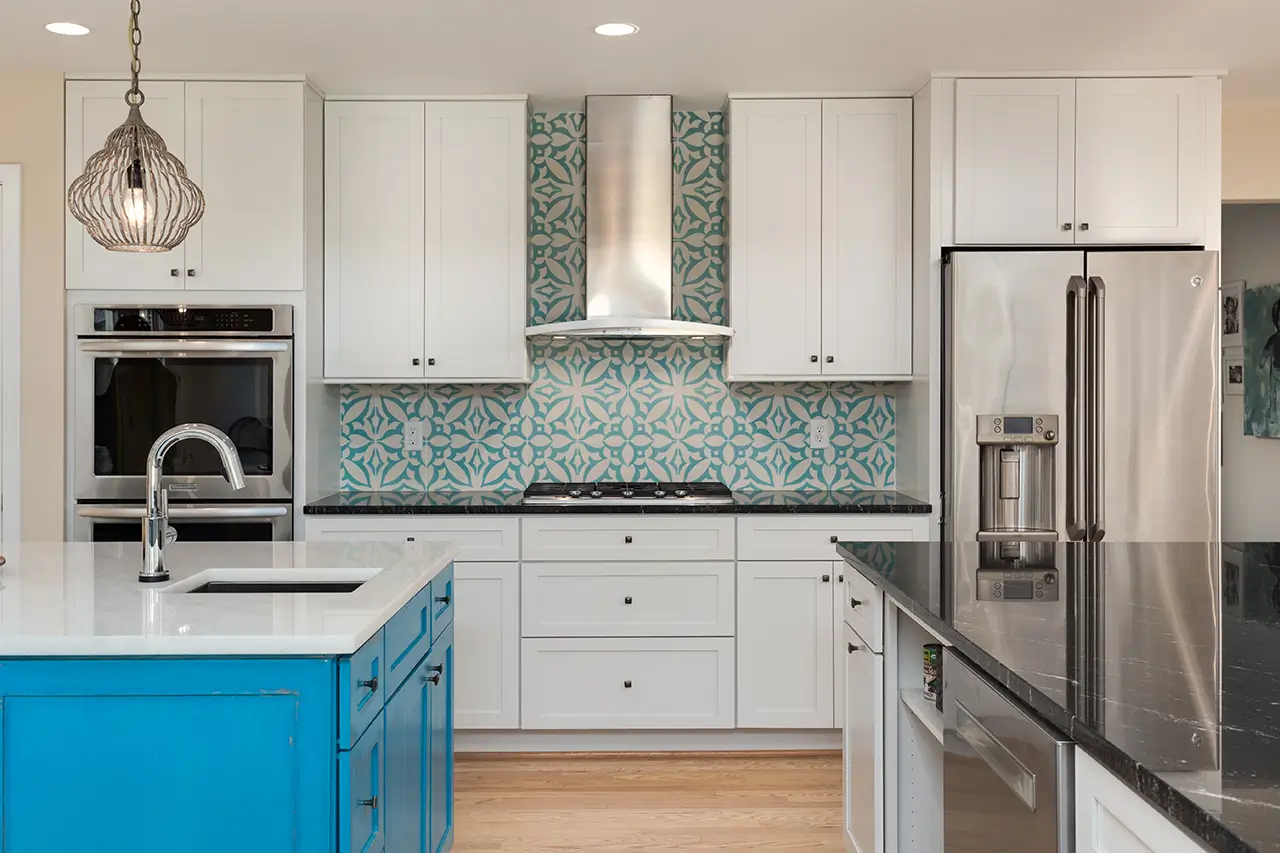 White kitchen with blue island and patterned tile.